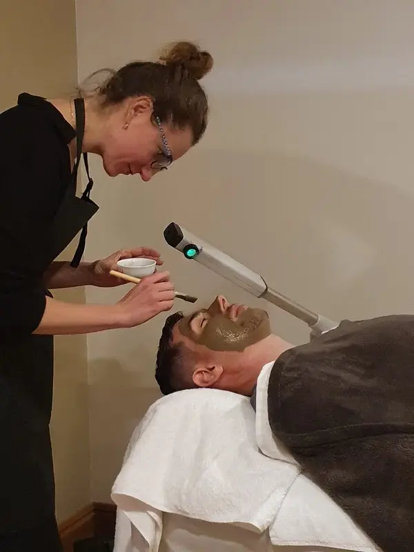 Therapist applying a facial mask during a treatment